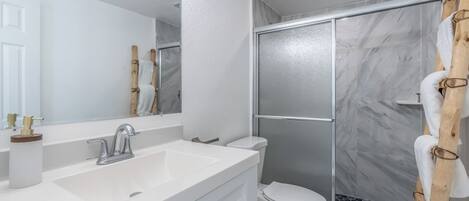 Un baño con lavamanos, espejo y retrete blanco.