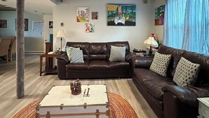 A living room with a brown leather sofa, a white coffee table, and a patterned rug.