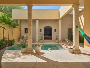 A pool area with columns, potted plants, and a hammock. - Casa Isabela Amazing Architecture in Merida Centro (Mérida)