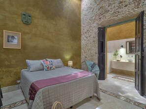 A bedroom with a bed, a nightstand, a wall-mounted picture, and a bathroom visible through an open door. - Casa Isabela Amazing Architecture in Merida Centro (Mérida)