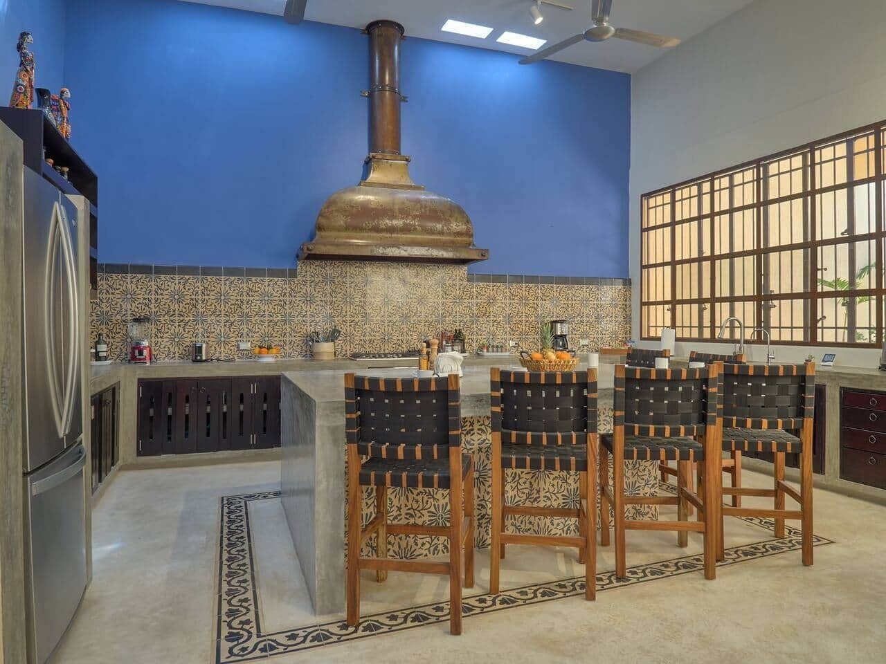 A kitchen with a central island, bar stools, a large stove, and a patterned backsplash.
