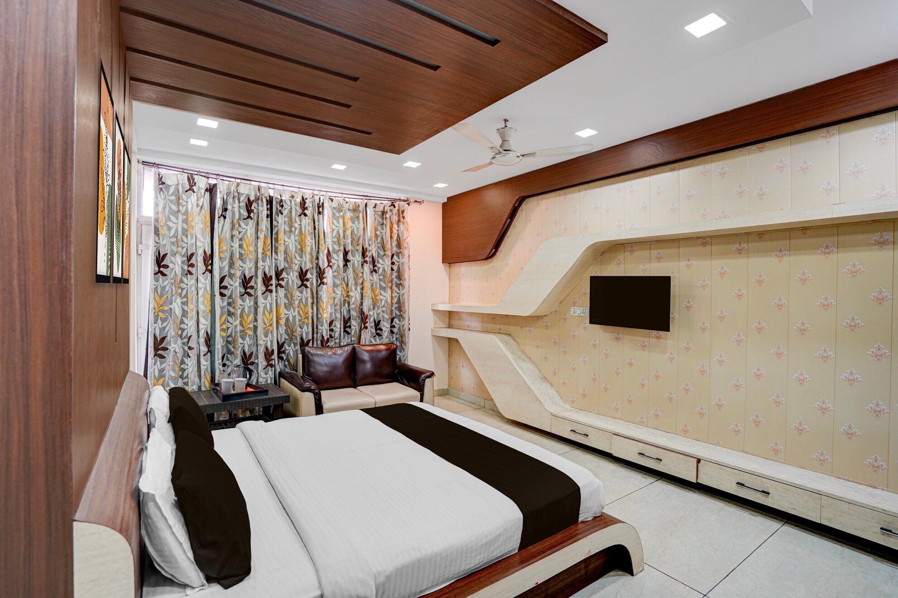 Habitación de hotel con cama, escritorio, silla, televisor y armario.