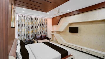 Habitación de hotel con cama, escritorio, silla, televisor y armario.