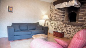 A living room with a sofa, a lamp, a stone wall, and a fireplace. - La Hulotte en Brocéliande - Yoga, seminars & group holidays 15 pers. (Saint-Malon-sur-Mel)