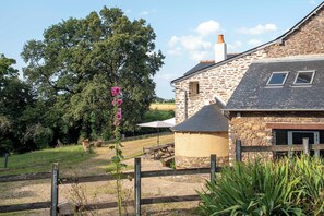 A stone building with a sloped roof, a wooden fence, and a picnic table. - La Hulotte en Brocéliande - Yoga, seminars & group holidays 15 pers. (Saint-Malon-sur-Mel)