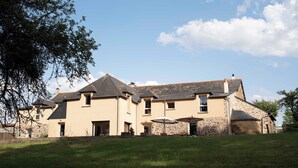 A two-story house with a stone facade, multiple windows, and a grassy yard. - La Hulotte en Brocéliande - Yoga, seminars & group holidays 15 pers. (Saint-Malon-sur-Mel)