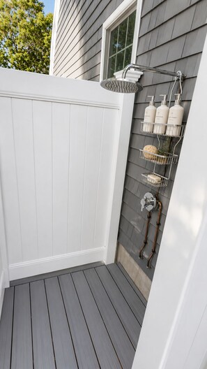 A small outdoor shower area with a white door, a metal showerhead, and a soap dispenser rack. - 3-bedroom, 2 bath Popponesset Cottage with AC - walk to beach and The Spit (Mashpee)