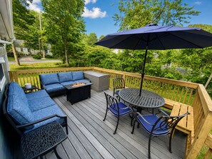 A deck with a sofa, chairs, a table, and an umbrella. - 3-bedroom, 2 bath Popponesset Cottage with AC - walk to beach and The Spit (Mashpee)