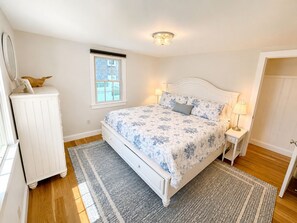 A bedroom with a bed, bedside tables, a dresser, a window, and a door. - 3-bedroom, 2 bath Popponesset Cottage with AC - walk to beach and The Spit (Mashpee)