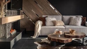Een moderne woonkamer met een open haard, een bank, een salontafel en een hanglamp.
