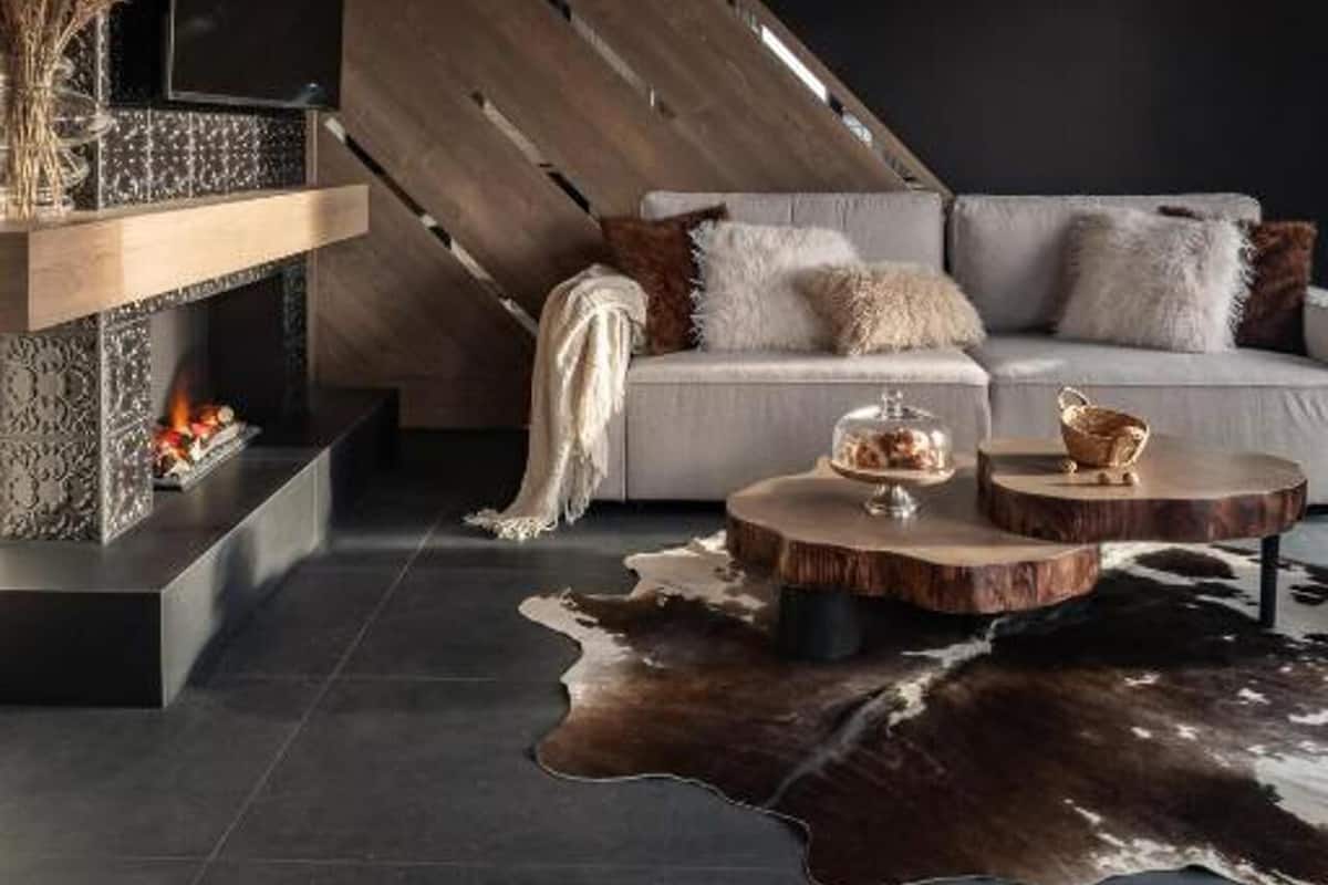 A modern living room with a fireplace, a sofa, a coffee table, and a hanging light fixture.