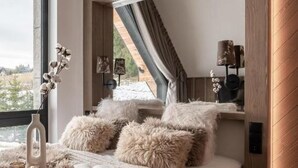 Een slaapkamer met een groot bed, zachte kussens, een hanglamp en uitzicht op de omgeving.
