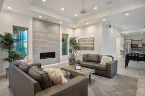 A modern living room with a fireplace, sofas, a coffee table, and a pool table. - Family Escape Near Zion, Pool, Private Hot Tub/Patio (Hurricane)