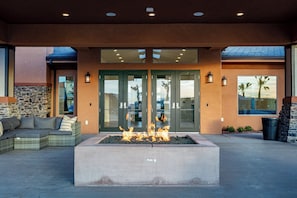 A fire feature in front of a building with a stone wall, a sofa, and a door with glass panels. - Family Escape Near Zion, Pool, Private Hot Tub/Patio (Hurricane)