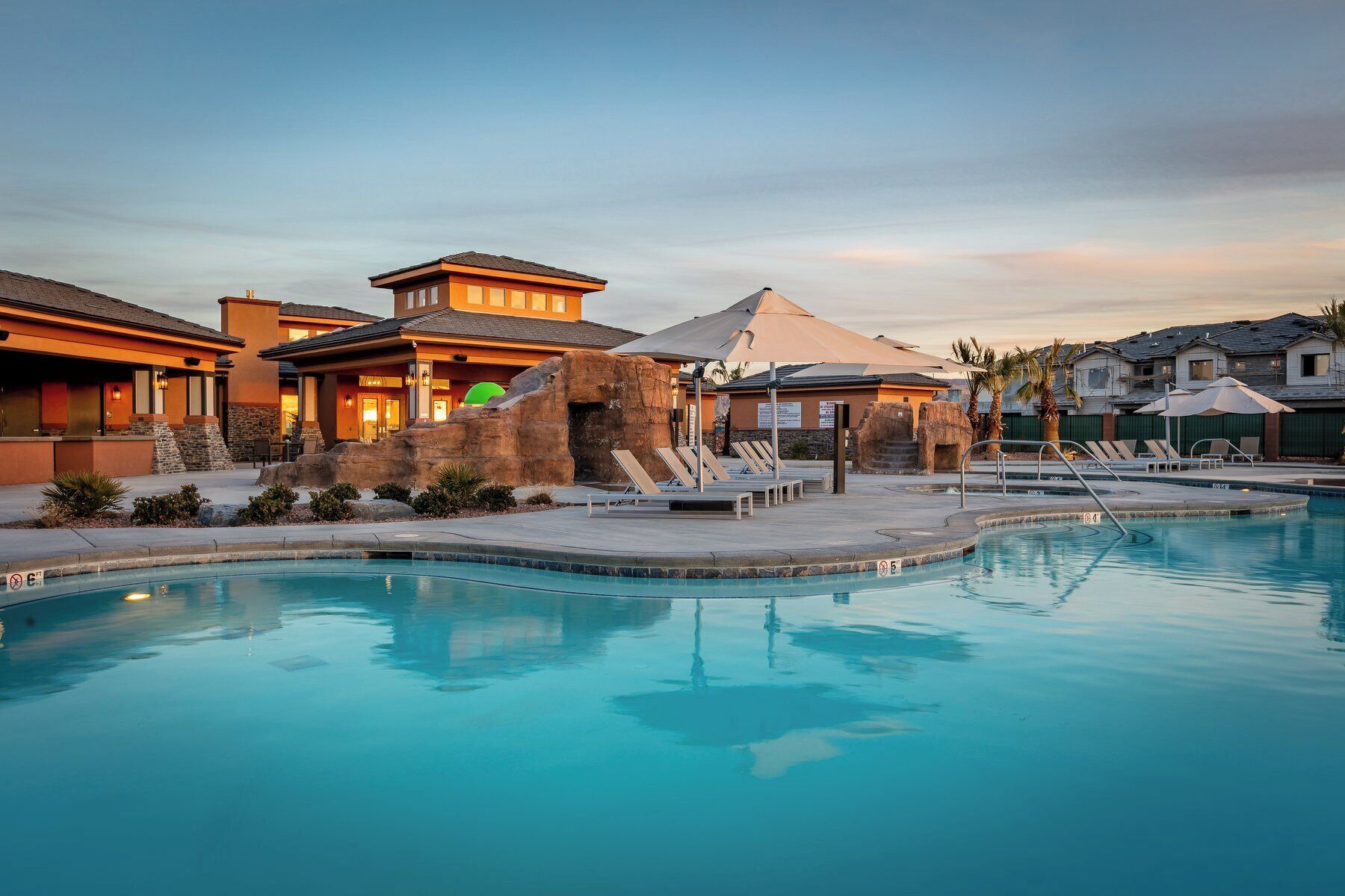 Un resort con piscina, sillas de descanso y una formación rocosa.