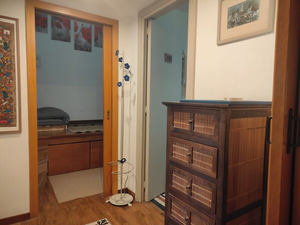 Een slaapkamer met een bed, een dressoir, een spiegel en een deur naar een andere kamer.