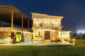 A two-story modern house with a swimming pool, outdoor seating, and a covered patio. - Unique Farmhouse by ELIVAAS (Noida)