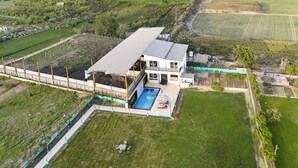 Ein modernes, zweistöckiges Haus mit Swimmingpool, umgeben von einem eingezäunten Garten und Feldern.