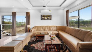 Ein modernes Wohnzimmer mit einer großen Couch, einem Glastisch und einem Deckenventilator.