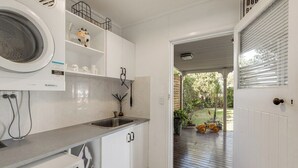 Una cucina con lavatrice, lavello e una porta che dà su un patio con un'automobilina.