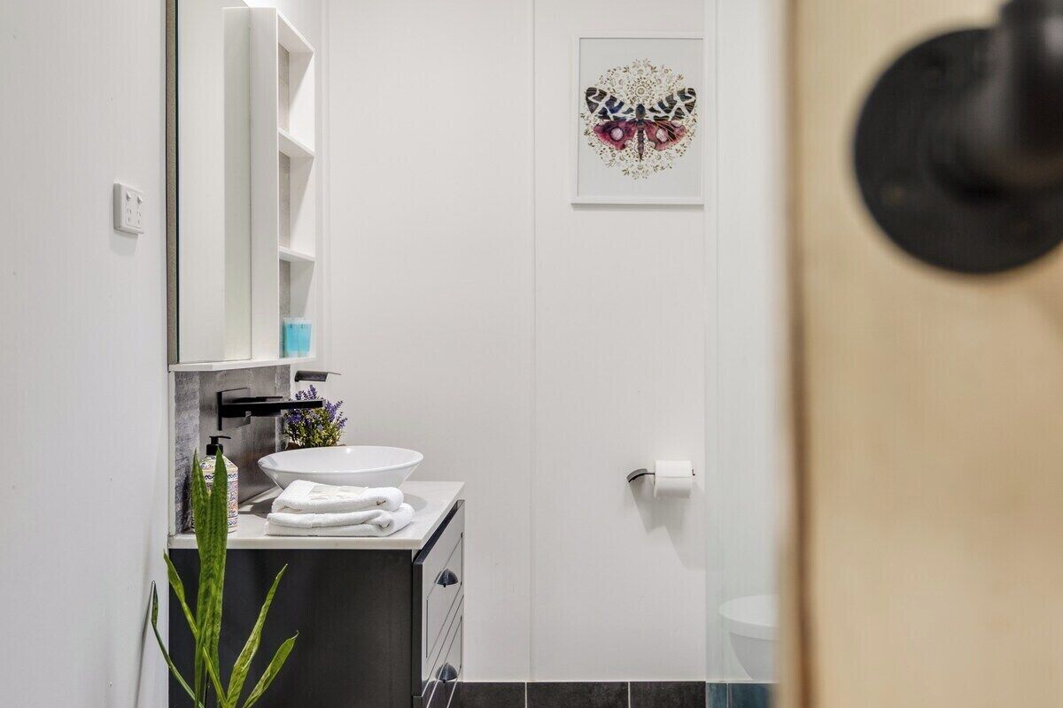 Une salle de bain avec un lavabo blanc, un miroir, un porte-serviettes et des toilettes.