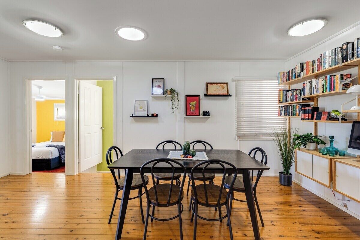 A dining area with a wooden table and chairs, a bookshelf, and a door leading to another room.