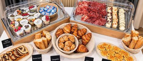 A buffet with various food items including pastries, bread, and desserts.