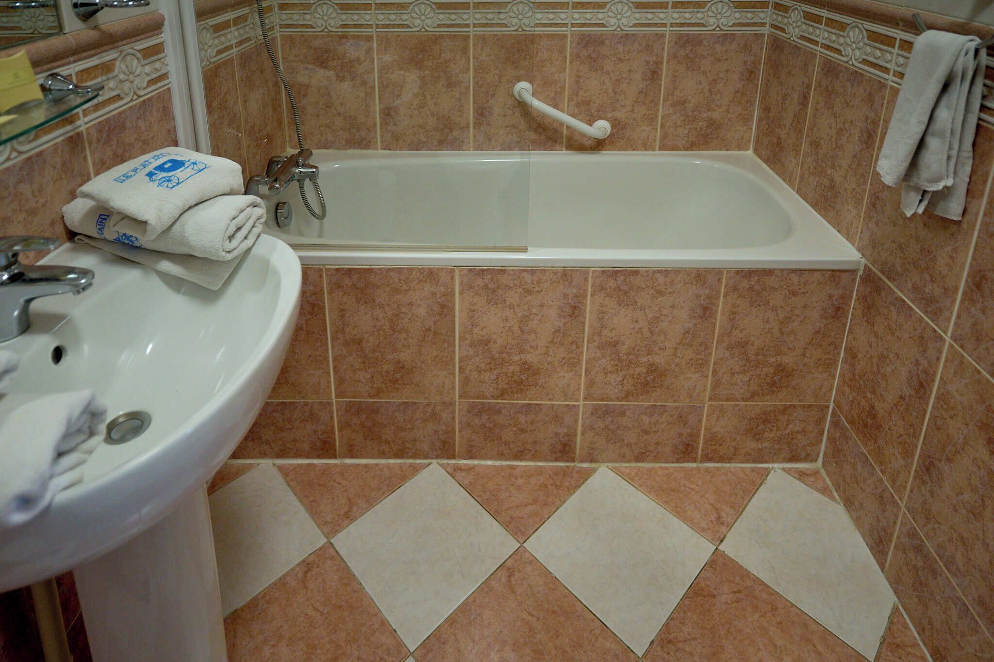 A bathroom with a bathtub, a sink, and a handrail.