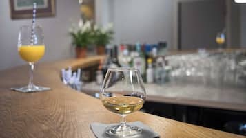 Zona de bar con una copa de vino blanco y un vaso de zumo de naranja sobre la barra.