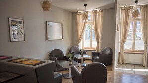 A modern room with a dining table, chairs, a small table with a plant, and large windows with curtains. - Hôtel Restaurant Le Plat d'étain (Brou)