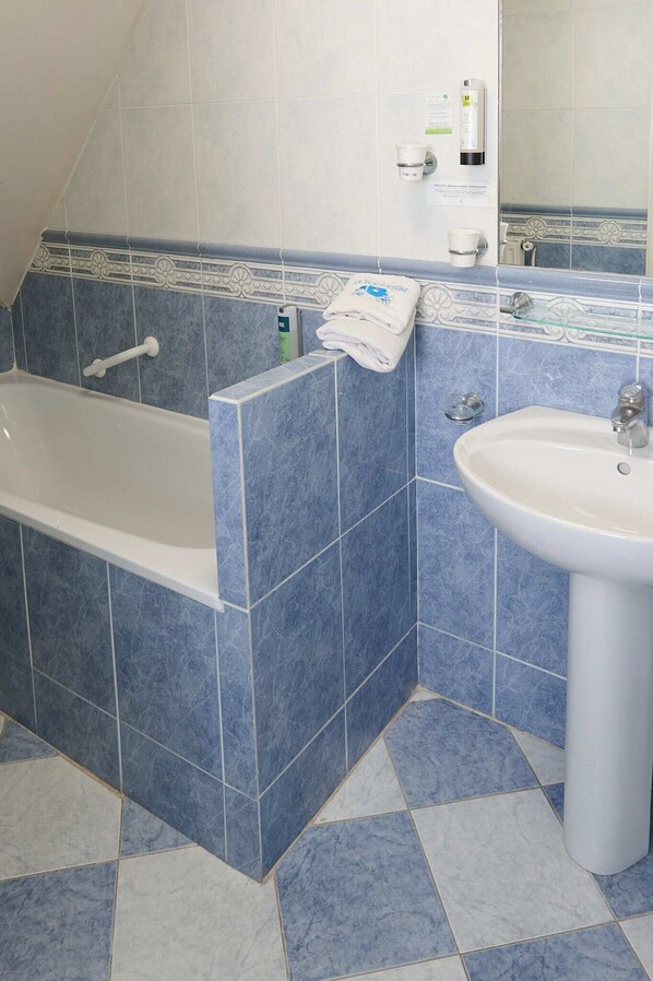 Une salle de bain avec une baignoire, un lavabo et des murs carrelés.