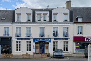 Un hotel con restaurante, salón y un coche estacionado frente a él.