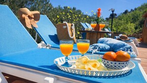 A sun lounger with a tray of food and drinks, a woven bag, and a blue and white patterned bowl. - Peaceful Gated Home, Fast Wifi for Remote Work, Private Pool, BBQ, Kids Area (Casabermeja)