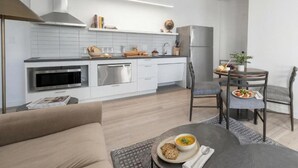 A modern kitchen with white cabinets, a built-in oven, and a dining area with a round table and chairs.