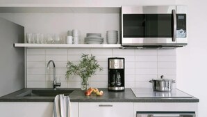 A modern kitchen with a stainless steel microwave, a coffee maker, and a pot on the counter.