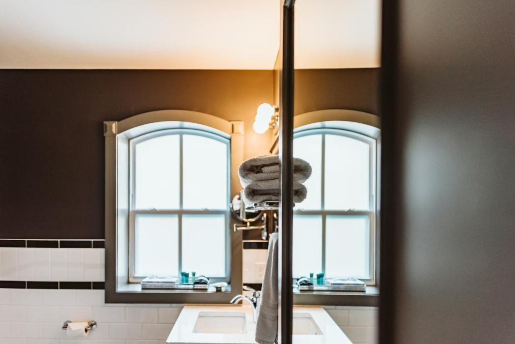 A bathroom with two sinks, a towel rack, and a window with a view.