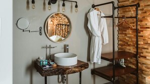 Une salle de bain avec un miroir rond, un lavabo rond, un porte-serviettes et un panneau mural en bois.