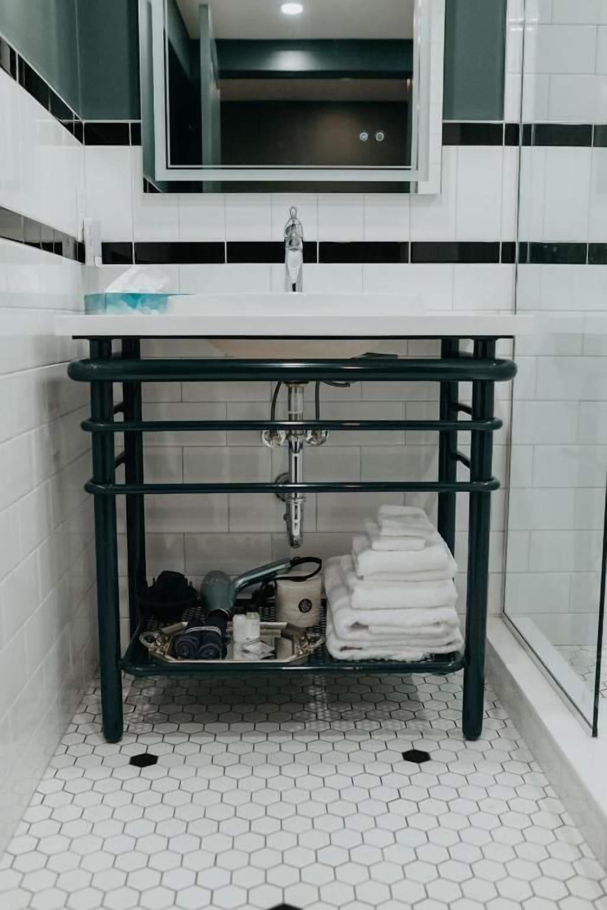 Ein Badezimmer mit einem weißen Waschbecken, einem grünen Metallregal und einem Boden mit sechseckigen Fliesen.