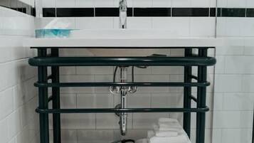 Ein Badezimmer mit einem weißen Waschbecken, einem grünen Metallregal und einem Boden mit sechseckigen Fliesen.
