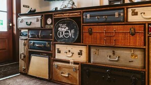 Un mur composé de vieilles valises, avec une pancarte indiquant : « The Grove Hotel ».
