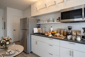 Een moderne keuken met een roestvrijstalen koelkast, een magnetron en diverse etenswaren op het aanrecht.