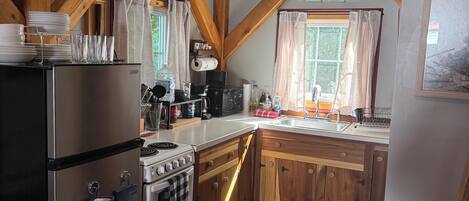 A kitchen with wooden beams, a stainless steel refrigerator, a stove, and a sink.