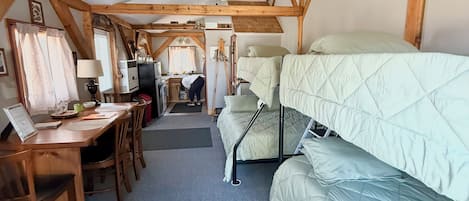 A room with a bunk bed, a desk with a computer, a chair, and a ceiling fan.