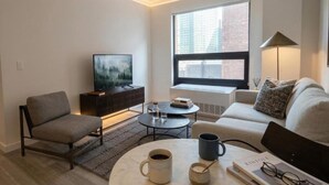 A modern living room with a sofa, armchair, coffee table, and a television.