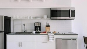 Una cucina moderna con un frigorifero in acciaio inossidabile, una macchina da caffè e un forno a microonde.