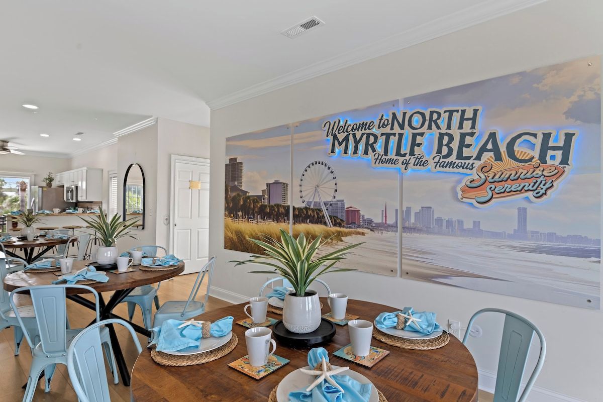 A dining area with a cityscape mural, a round table set with placemats, and light blue chairs.