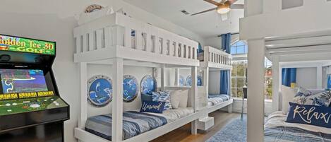 Quarto com beliche, console de videogame de golfe em 3D, decoração náutica e vista para o exterior.