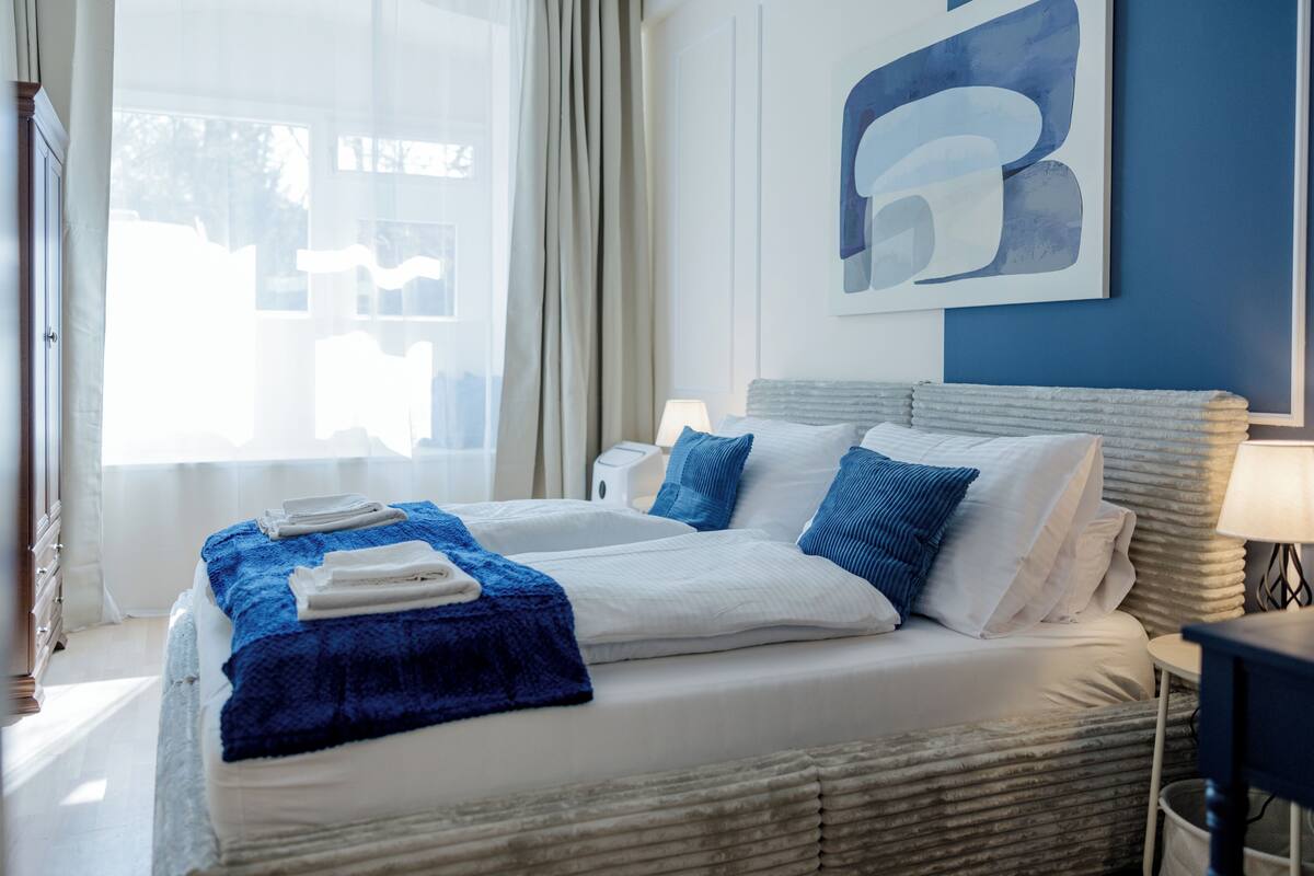Ein Hotelzimmer mit einem Bett, einem Nachttisch, einer Lampe und einem großen abstrakten Gemälde an der Wand.
