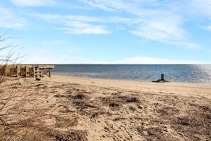 A sandy beach with a wooden structure, possibly a pier or walkway, extending into the water. - East End Studio With Private Beach Access (Provincetown)