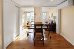 A dining area with a wooden table and chairs, a sofa, and a lamp. - East End Studio With Private Beach Access (Provincetown)